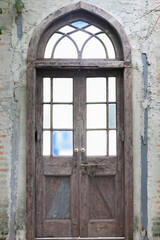 front view of old wooden door with color glass on brick cement wall