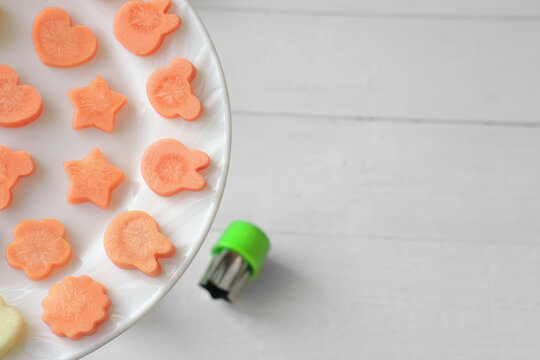 Funny Food For Picky Eaters Kids. Carrots Cut In Various Shapes, Bunny, Stars And Flowers Made Of Carrots. Food Cutter Near A Plate. Selective Focus.