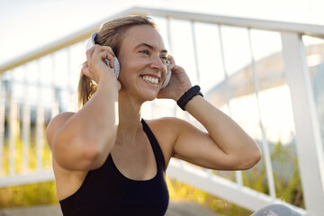 Happy athletic woman listening music over headphones outdoors.