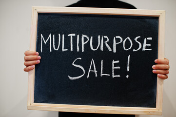 Multipurpose sale written on blackboard. Black friday concept. Boy hold board.