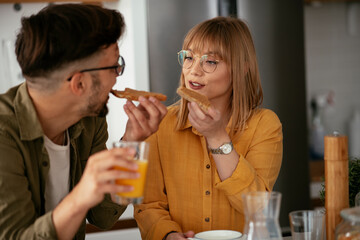 Young couple making breakfast at home. Loving couple eating sandwich in kitchen...