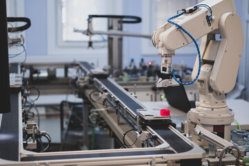 Industry 4.0 concept; artificial intelligence in smart factory prototype. The robot picks up the product from an automated car on the production line. Focus on the robotic arm's gripper.