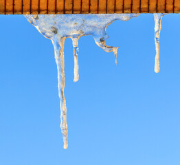 Icicles in winter against a blue sky.