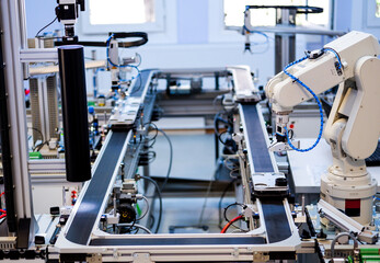 Industry 4.0 concept; artificial intelligence in smart factory prototype. The robot picks up the product from an automated car on the production line. Focus on the robotic arm's gripper.