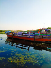 Fototapeta na wymiar Wooden boat standing near river bank , solitude and calmness, relaxation