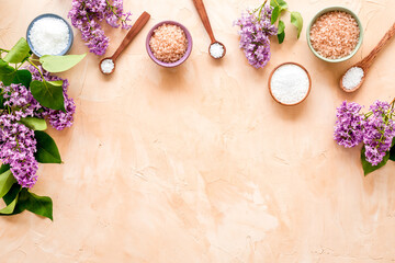 Fototapeta na wymiar Frame of sea bath salt and purple flowers, top view