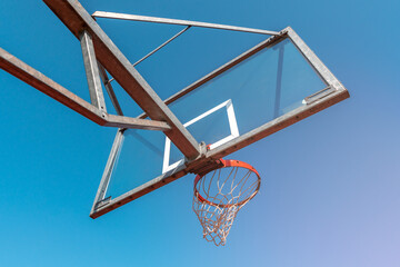 Naklejka premium Bottom view of basketball hoop and clear blue sky