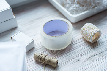 Packaging tools, transparent scotch roll and ropes on wooden desk