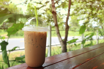Iced coffee in plastic mug on wood and natural background.