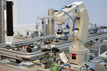 Industry 4.0 concept; artificial intelligence in smart factory prototype. The robot picks up the product from an automated car on the production line. Focus on the robotic arm's gripper.