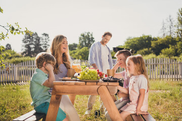 Photo full big family five people three little children dad make fried meat mom have frindly chat kids wait dinner table sunny day house green park fenced backyard outside outdoors