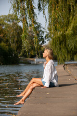 girl in shirt and skirt on the background of the river in the park