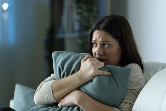 Scared woman embracing pillow at home in the night