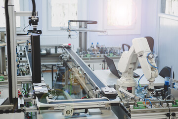 Industry 4.0 concept; artificial intelligence in smart factory prototype. The robot picks up the product from an automated car on the production line. Focus on the robotic arm's gripper.