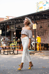 a girl in light clothes walks against the background of a cafe in the city
