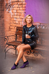 beautiful girl in black clothes sits with a cup of coffee in her hand and smiles