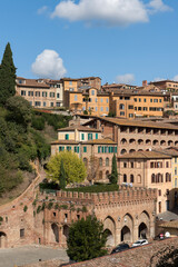 Fototapeta na wymiar View of old medieval houses on a steep hill of Siena, Italy