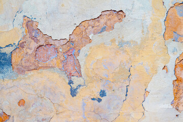 damaged weathered multicolored coating of paint of concrete building wall with many patches