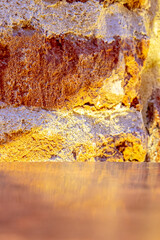the edge of metallic table and damaged weathered burnt brick building wall with artificial moddy...