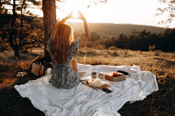 young and happy woman enjoying amazing picnic scenery with beautiful sunset.