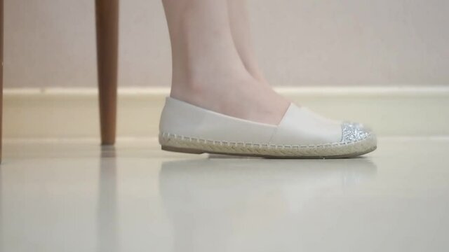female feet in white shoes shaking on white floor. foot tapping concept.