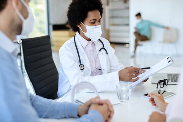 African American doctor going through medical record while having appointment with a couple.