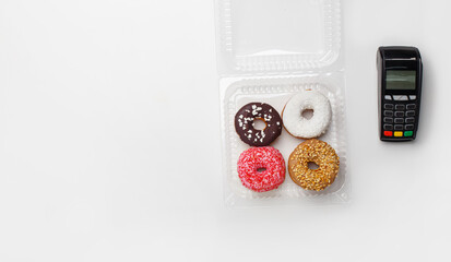 Sweets and bakery order takeaway. Donuts with glaze and crumb in transparent container for delivery and modern contactless terminal