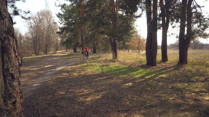 Cyclist. Caucasian sport woman rides along the track in the forest on a spring sunny day. Riding a sportsman girl on a mountain bike on a rural trail in nature. Outdoor sports