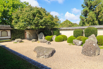 Japanese zen garden with raked pebbles, neatly trimmed bushes, and surrounding wall