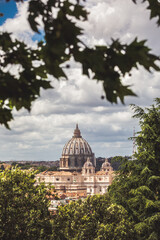 Fototapeta premium Dome of St. Peter in the Vatican city in Rome in Italy in the middle of the trees. Renovation works in the cathedral with scaffolding.