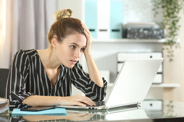 Worried businesswoman discovering online mistake on laptop