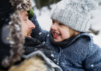 Close-up of father with small son in snowy winter nature, talking in.