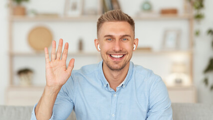 Guy sitting at home on the sofa and waving