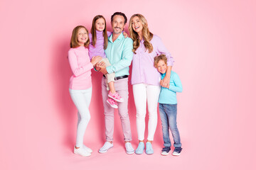 Fototapeta premium Full length photo of positive idyllic family enjoy together spend weekend day daddy hold smallest kid mommy embrace hug cuddle son isolated over pink color background