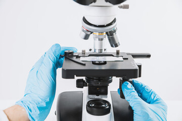 Scientist looks through a microscope in a laboratory. Medical and pharmaceutical concept. Laboratory research, medical and scientific research. Blood, virus, biology tests.