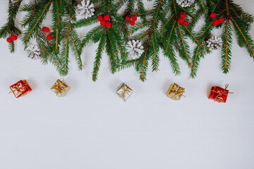 Christmas border on white wooden background composed of fresh fir branches and ornaments in various colors . Copy space.