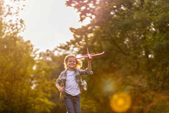 Little Boy Playing With Toy Plane In Park
