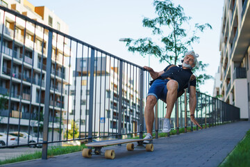 Mature man riding skateboard outdoors in city, falling down and accident concept. © Halfpoint