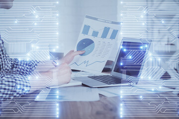 Technology theme hologram with man working on computer on background. High tech concept. Double exposure.