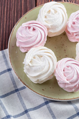 Pink and white meringue cookies on green plate