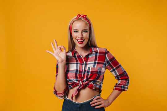 Image of joyful blonde pinup girl smiling and gesturing ok sign