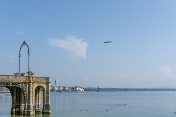 view of the Schosssteg or castle pier on Lake Constance in Friedrichshafen with a Zeppelin flying overhead © makasana photo
