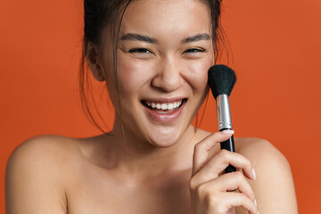 Image of cheerful shirtless asian girl posing with powder brush