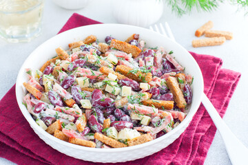 Salad with red beans, smoked sausage, cheese and crackers in a white bowl, horizontal
