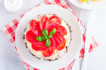 Festive layered salad with fried champignons, smoked chicken, eggs and cheese, garnished with fresh tomatoes, selective focus