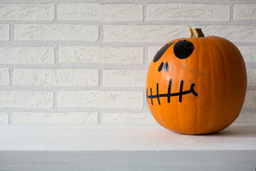 Orange halloween pumpkin, with eyes, nose and mouth, isolated on white bricks background.