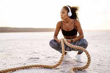 Image of african american sportswoman working out with battle ropes