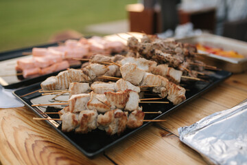 Preparing salmon, chiken and pork on party outdoors