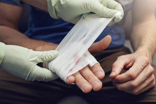 first aid - doctor traumatologist bandaging patient injured hand
