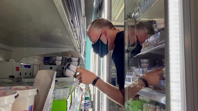 Man in protective mask buying yougurt in Aldi supermarket